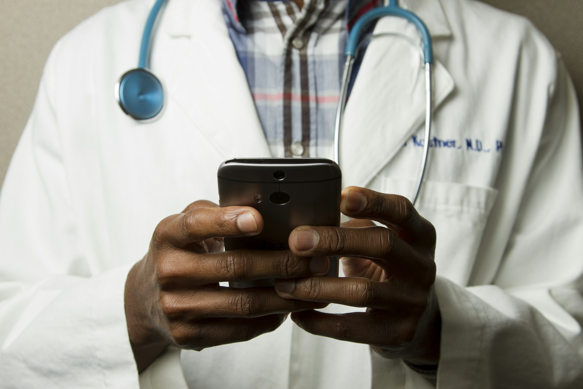 A clinician using a digital device while wearing a stethoscope